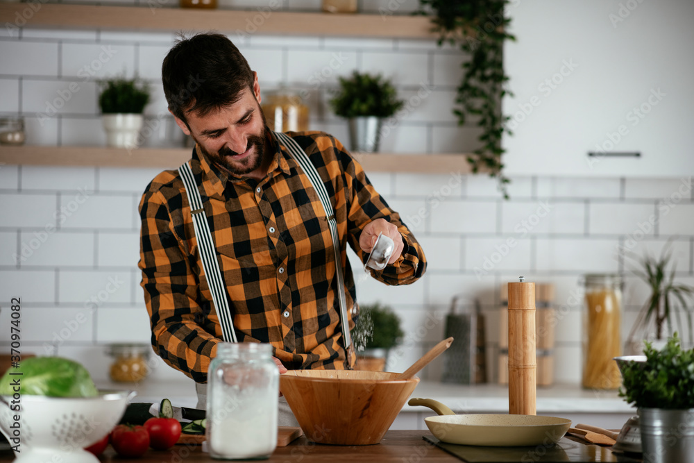 Portrait of handsome man in kitchen. Young man preparing delicious food.. Portrait of handsome man in kitchen. Young man preparing delicious food..