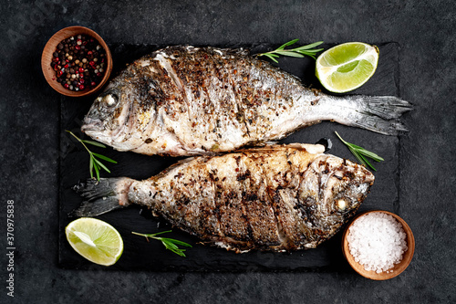 grilled dorado fish with ingredients on stone background photo