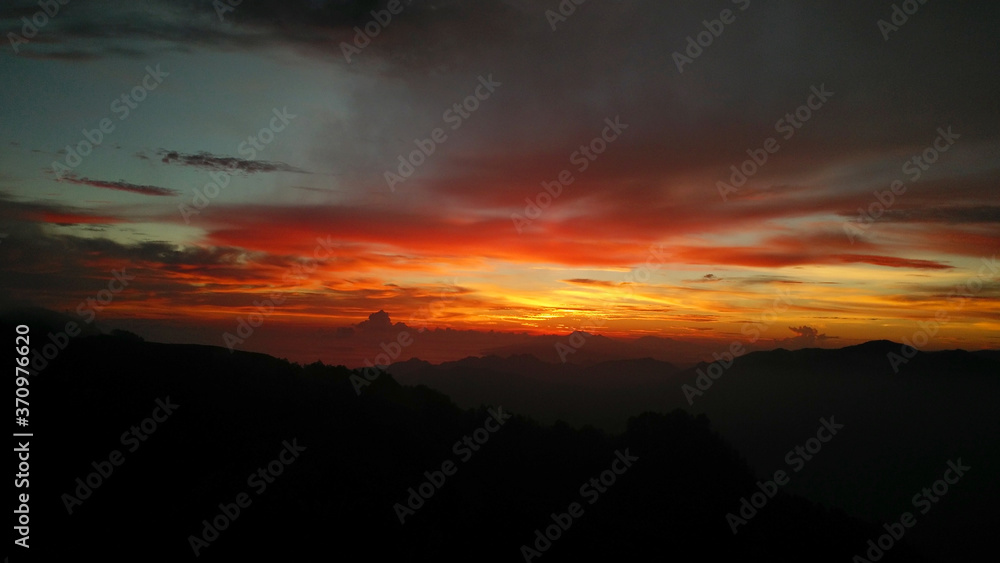 beautiful orange sunset on mountain with blue lake and white smoke and fantastic nature.