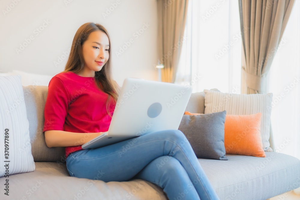 Portrait beautiful young asian woman use laptop computer on sofa in living area Portrait beautiful young asian woman use laptop computer on sofa in living area