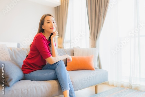 Portrait beautiful young asian woman relax smile on sofa in living area