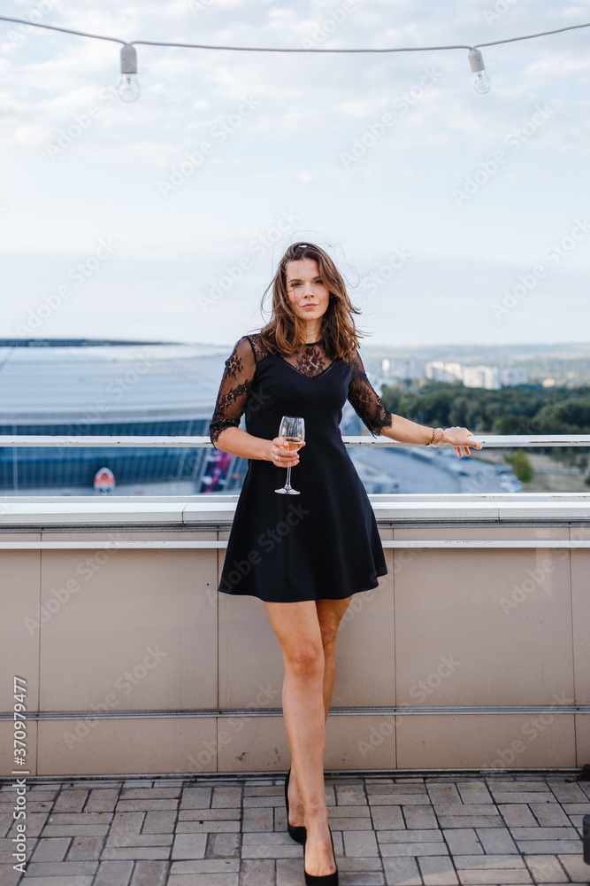 woman with a glass of wine on the balcony against the background of the city