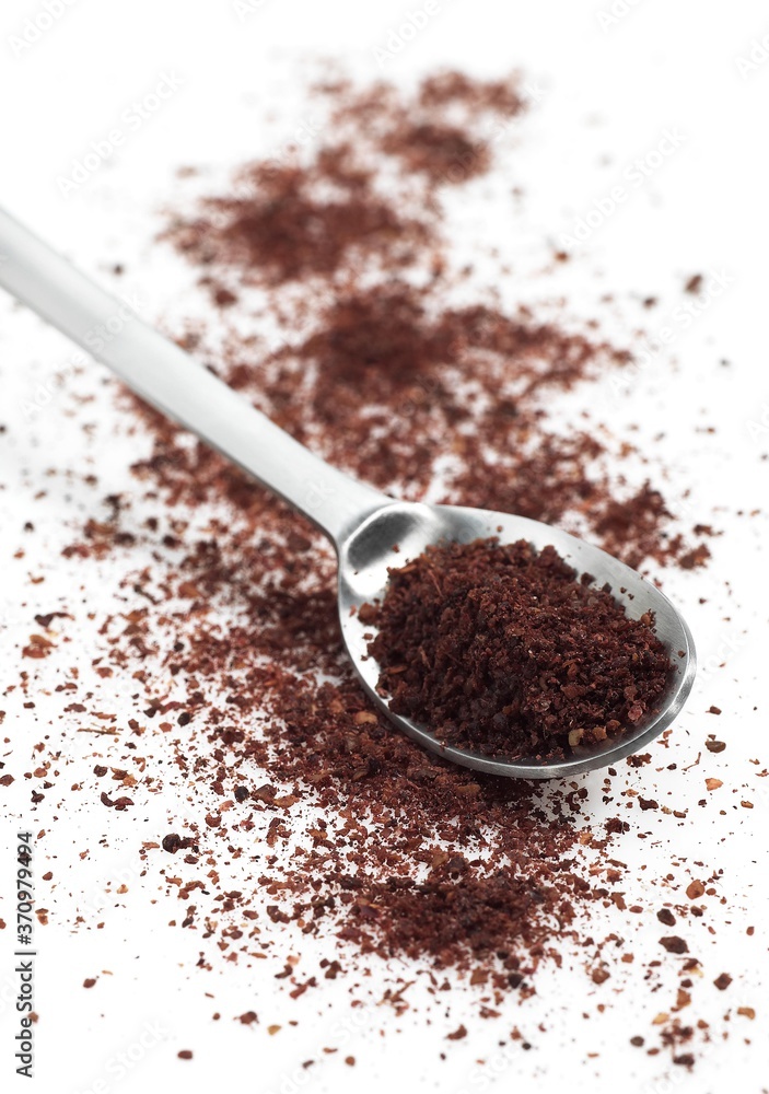 Sumac Powder, Spice in a Spoon against White Background Sumac Powder, Spice in a Spoon against White Background