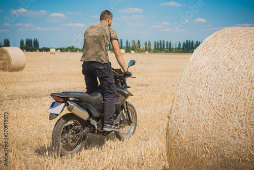 Young man on a motorcycle at field, hobby of modern people, lifestyle 