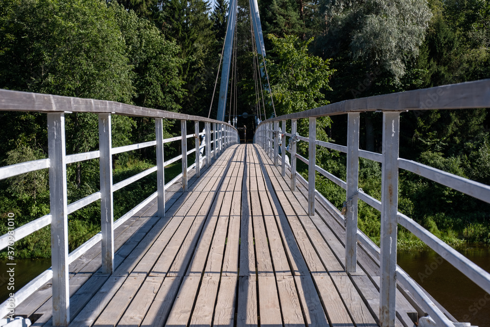 cable-stayed bridge over the river with wooden plank floor and forest in the background cable-stayed bridge over the river with wooden plank floor and forest in the background