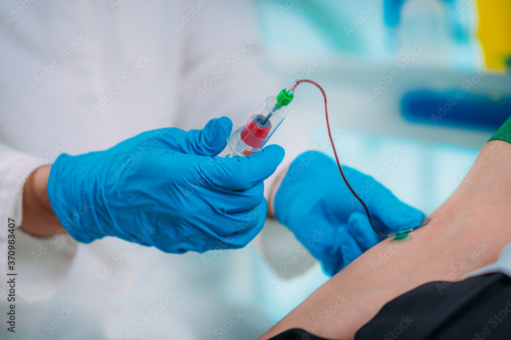 Medical worker with PPE taking blood sample from patient in a hospital Medical worker with PPE taking blood sample from patient in a hospital