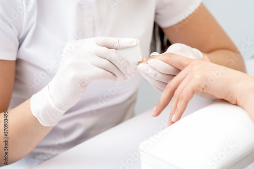 Close up of woman receiving manicure with nail file by manicurist at nail salon