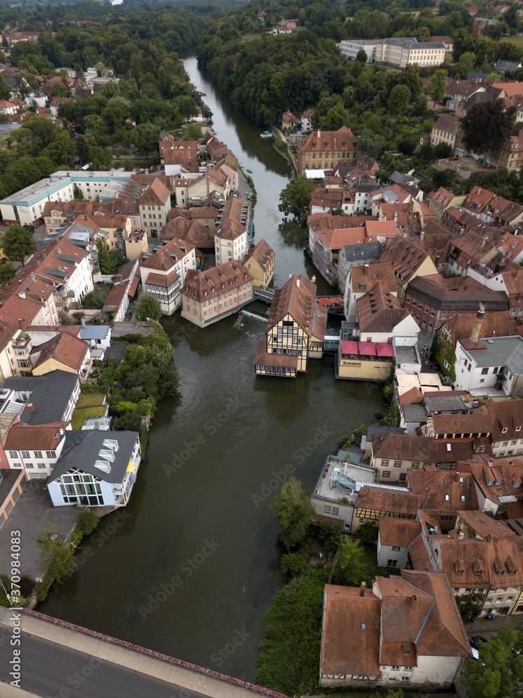 Aerial view of old town hall in Bamberg, Bavaria, Germany. House above river Main. Вridge, boats ancient historic half-timbered buildings with orange roofs. Beautiful cityscape.