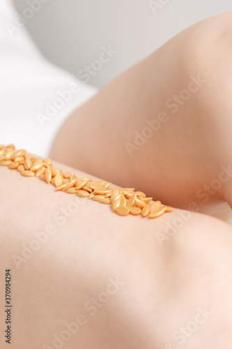 Wax beans or seed in row on legs of young woman lying on white background