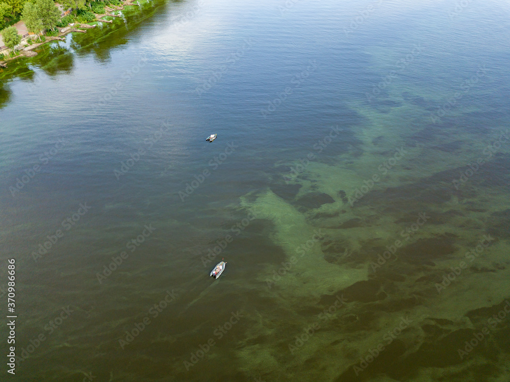 Aerial drone view. Fishing boat on the water. Algae bloom in the water, clouds are reflected.