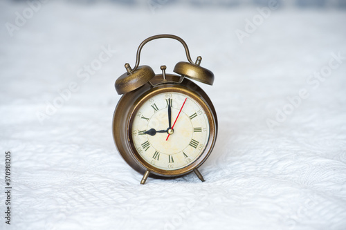 Retro clock stands on the bedspread in the bedroom. Time to get up