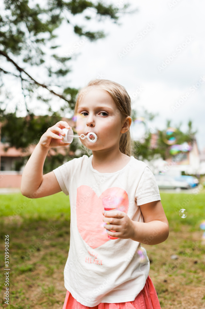 Cheerful girl inflates soap bubbles