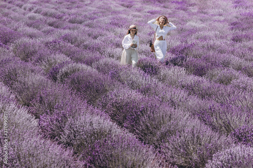 A young woman and her teendage daugher are enjoying a bright sunny day in the field of blooming lavender