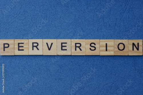 gray word perversion in small square wooden letters with black font on a blue background photo