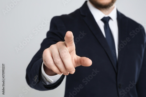 Businessman touching something against grey background, focus on hand