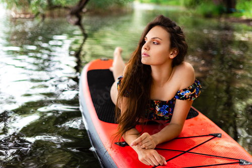 beautiful girl relaxing at the lake on a stand up paddle board