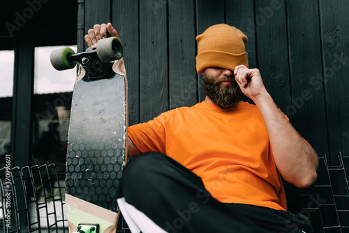Bild auf Leinwand Handsome young stylish hipster guy with beard with a skateboard
