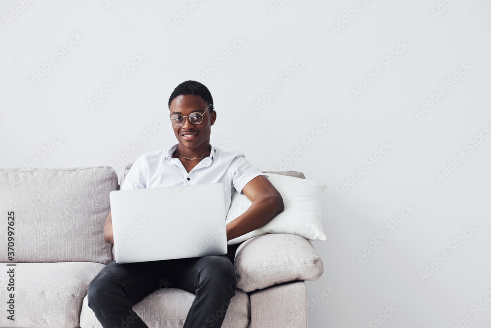 Young african american man in formal clothes sitting indoors with laptop in hands Young african american man in formal clothes sitting indoors with laptop in hands
