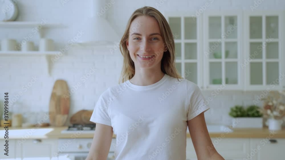 Happy young woman with braces smiles in the background of her kitchen, looking at the camera Happy young woman with braces smiles in the background of her kitchen, looking at the camera