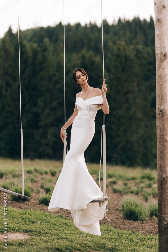 Beautiful bride with bouquet flowers stands on forest background. beautiful bride in delicate dress outdoors. Close up portrait of young bride in park in sunny weather wooded area. Beautiful bride with bouquet flowers stands on forest background. beautiful bride in delicate dress outdoors. Close up portrait of young bride in park in sunny weather wooded area.