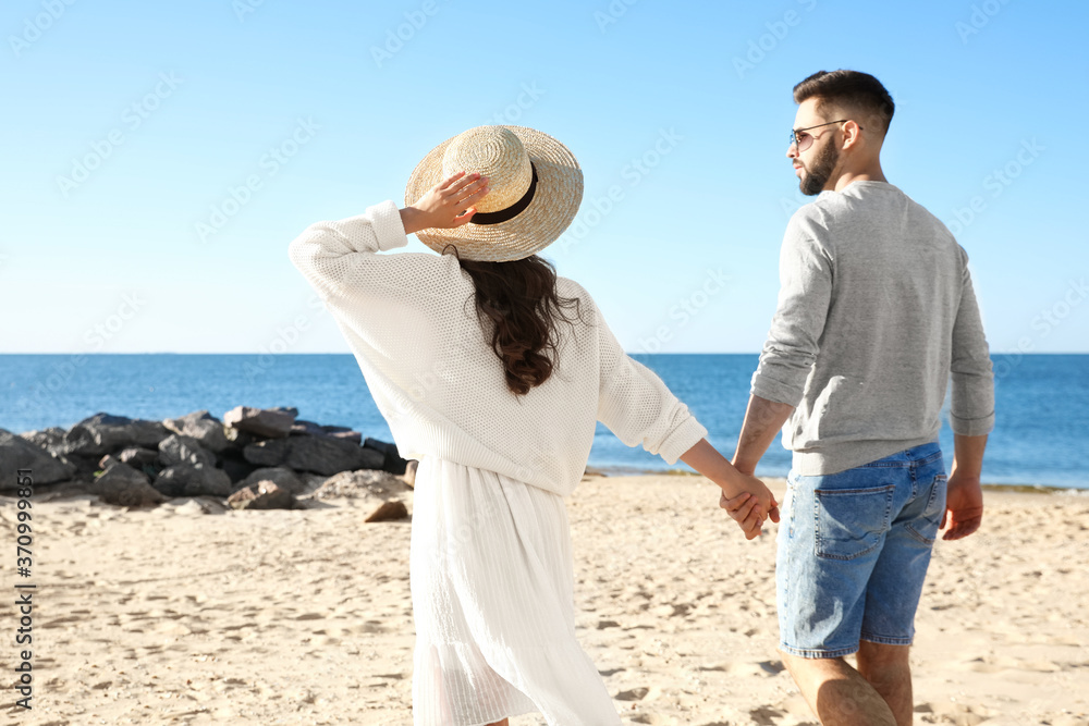 Happy young couple walking on beach near sea. Honeymoon trip Happy young couple walking on beach near sea. Honeymoon trip