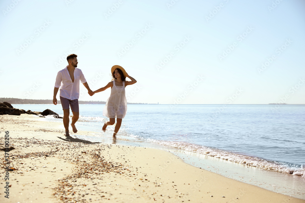 Happy young couple running on beach near sea. Honeymoon trip