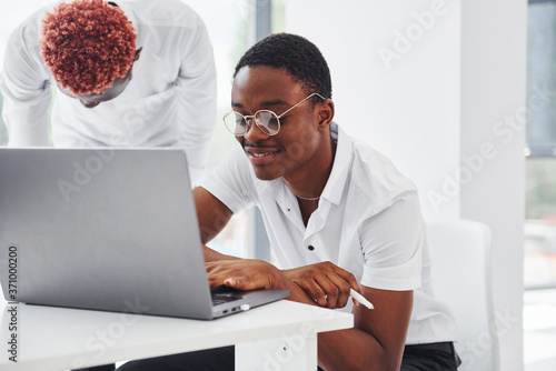 Sitting with laptop. Group of african american business people working in office together © standret