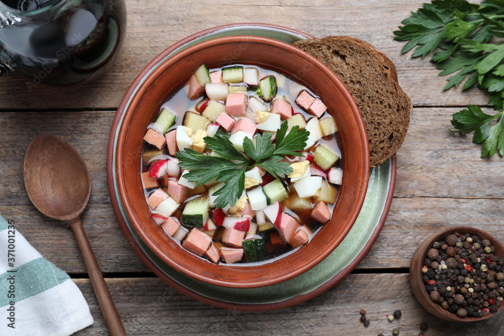 Delicious cold okroshka with kvass served on wooden table, flat lay. Traditional Russian summer soup