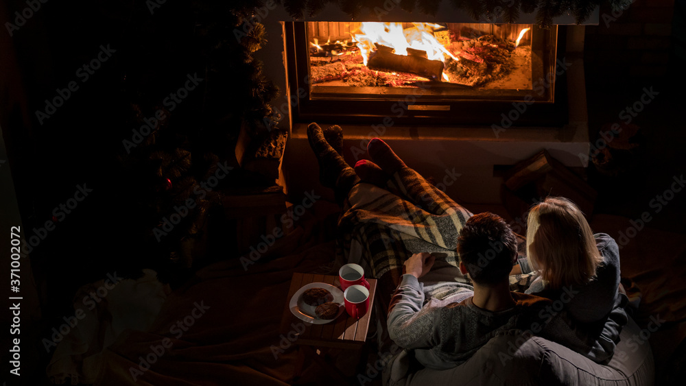 Young couple admires the fire in the fireplace, top view