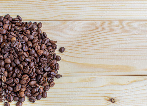 Lots of coffee beans on a wooden background. There is a place for insertion