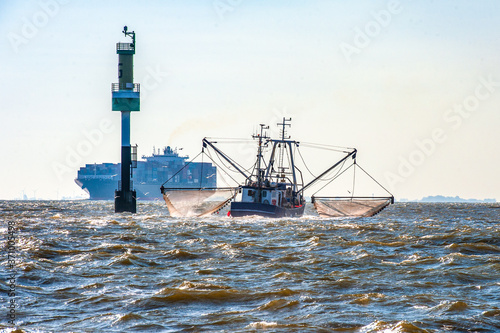 GERMANY, ELBE. Encounter of a crab cutter fishing in the mouth of the Elbe river with an outbound container ship