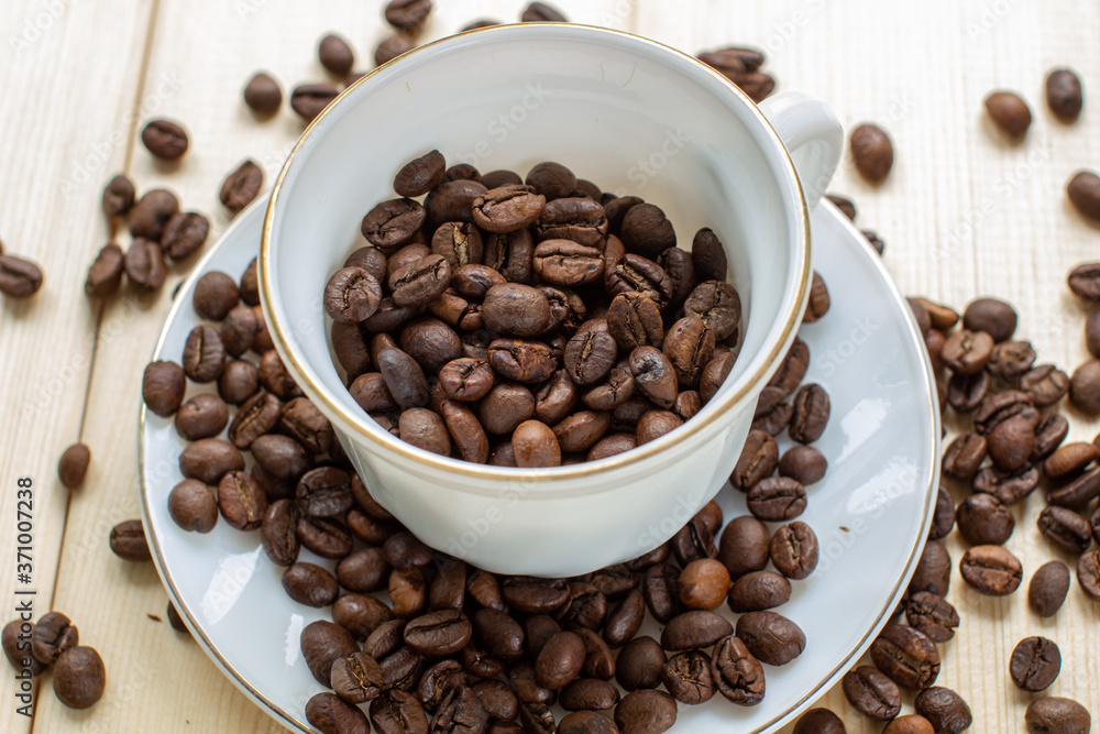 White mug with Cup of coffee beans on wooden background with selective focus and crop fragment White mug with Cup of coffee beans on wooden background with selective focus and crop fragment