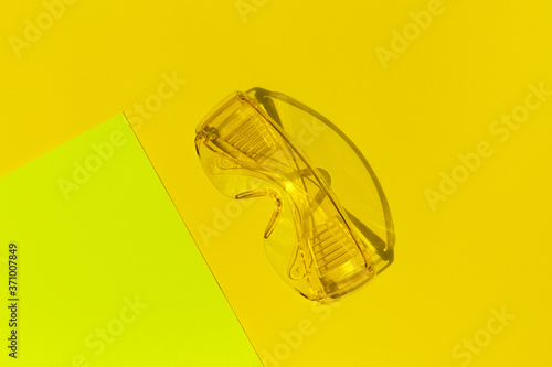 Transparent tinted glasses on yellow background. Creative monochrome layout. © Androlia