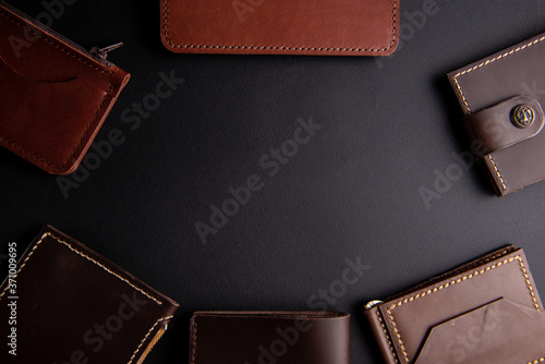 beautiful background wallets made of genuine leather of brown color made by hands are laid out on a black table. view from above. With space for an inscription. Leather craft concept.