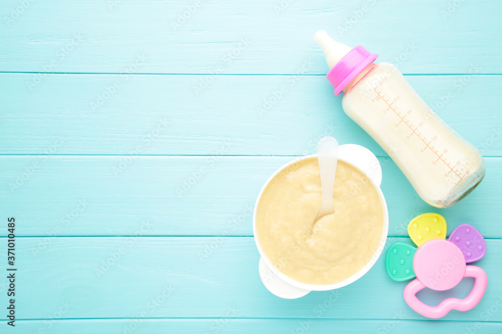 Milk and bowl with porridge for baby on blue background Milk and bowl with porridge for baby on blue background