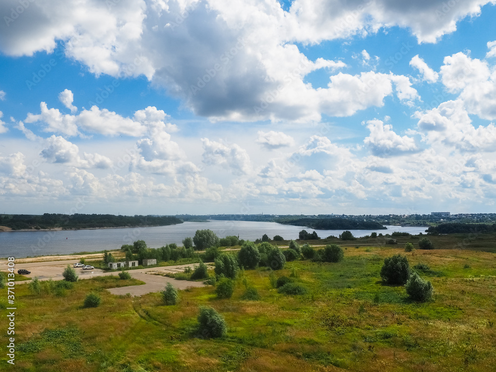 Fototapeta premium photo of a large field next to a river above a cloudy sky