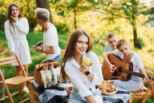 Woman eats apple. Group of young people have vacation outdoors in the forest. Conception of weekend and friendship