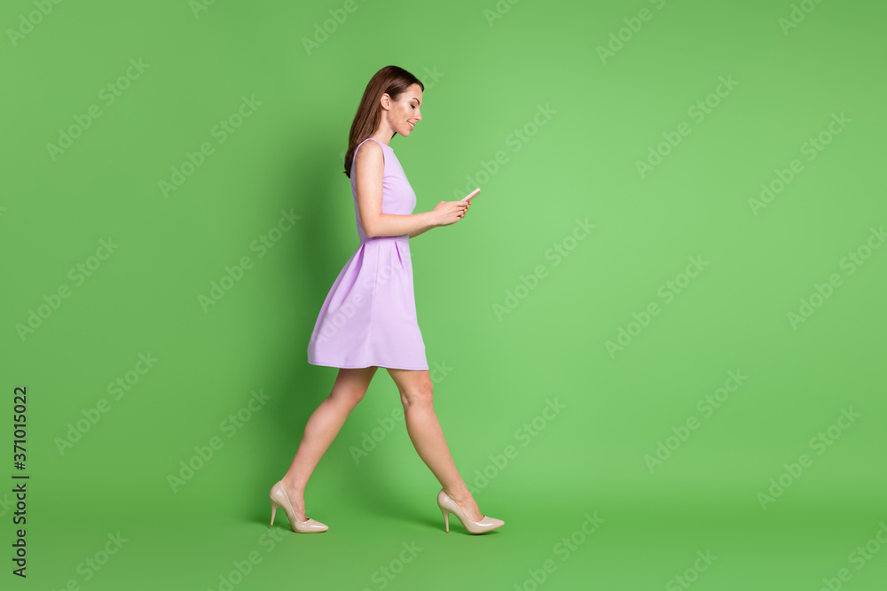 Full size profile photo of adorable pretty lovely young girl lady go empty space look telephone type chat blogging free communication wear purple dress isolated pastel green color background Full size profile photo of adorable pretty lovely young girl lady go empty space look telephone type chat blogging free communication wear purple dress isolated pastel green color background
