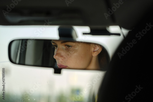 Reflection of young female face and eyes in rearview mirror of a car. Woman driver. Selective focus. © Мaksim G