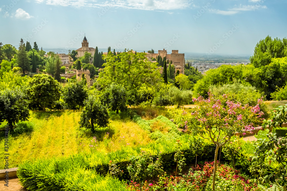 Summer gardens lead towards the Alhambra Palace and the city of Granada in the distance in the summertime
