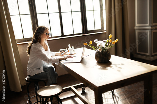 Attractive business woman working with laptop at the kitchen. Work from home concept .