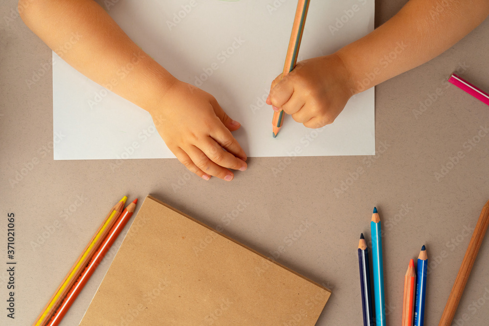 Kid's hands writing in open notebook, top view, copy space Kid's hands writing in open notebook, top view, copy space