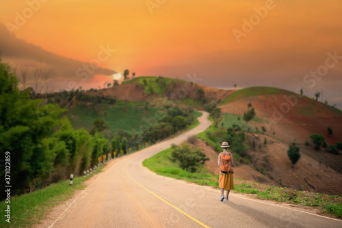 Lonely girl walking on the road with a backpack.