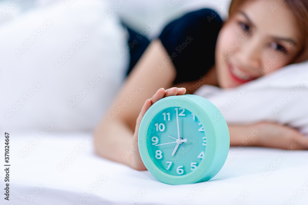The woman woke up in the morning with a bright smile. And an alarm clock placed on the bed The woman woke up in the morning with a bright smile. And an alarm clock placed on the bed