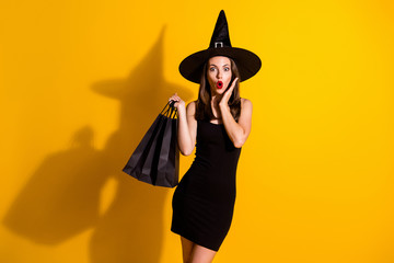 Portrait of her she nice attractive pretty amazed wondered stunned cheery thin lady wizard carrying new clothes season bargain news isolated bright vivid shine vibrant yellow color background