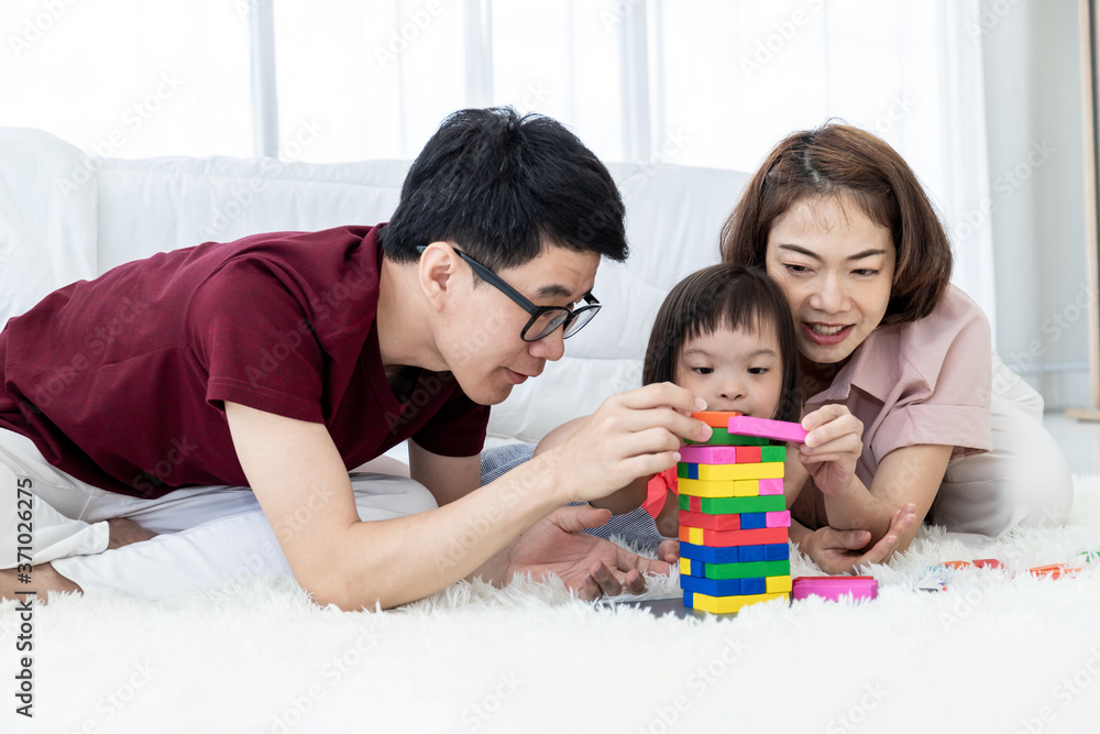 A young girl with dysfunction, brain learning disabilities,Down Syndrome constellation playing, and learning a multicolored wooden toy . A young girl with dysfunction, brain learning disabilities,Down Syndrome constellation playing, and learning a multicolored wooden toy .