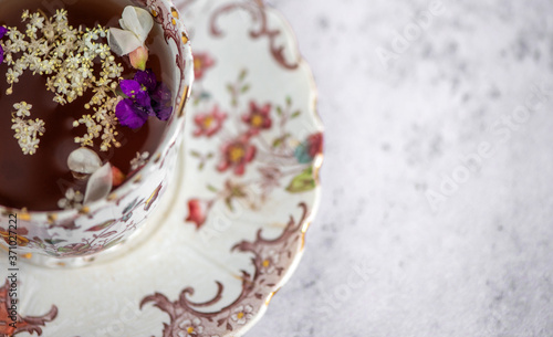 Closeup of a floral vitage tea cup with some fresh flower petals