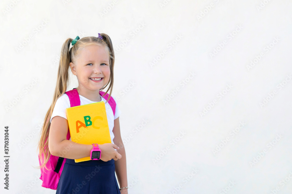 schoolgirl stands with a backpack and a textbook. copy space schoolgirl stands with a backpack and a textbook. copy space