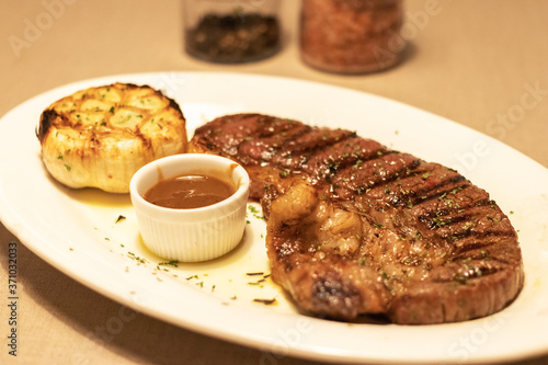 Medium grilled strip loin beef steak with pepper sauce in warm light at restaurant.