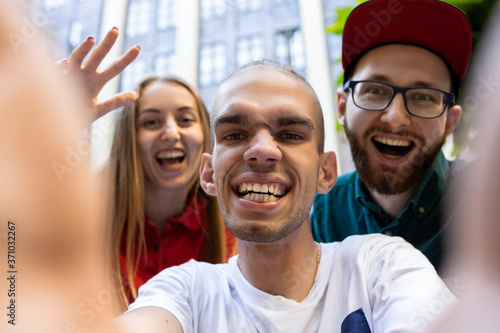 Selfie time. Group of friends taking a stroll on city's street in summer day. Handicapped man with his friends having fun. Inclusion and diversity concept, normal lifestyle of special groups of photo